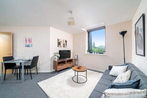 Ein modernes Wohnzimmer mit Essbereich, einer Couch, einem Fernseher und Kunstwerken an den Wänden.