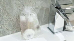 Un lavabo con una bottiglia di vetro trasparente contenente un liquido bianco, una bottiglia trasparente con tappo bianco e un'altra bottiglia con tappo bianco.