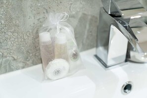 Ein Waschtisch mit einer klaren Glasflasche, die eine weiße Flüssigkeit enthält, sowie zwei weitere Flaschen mit weißen Verschlusskappen.