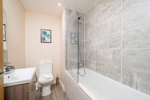 Ein Badezimmer mit Toilette, Waschbecken und einer Dusche mit Glaswand.