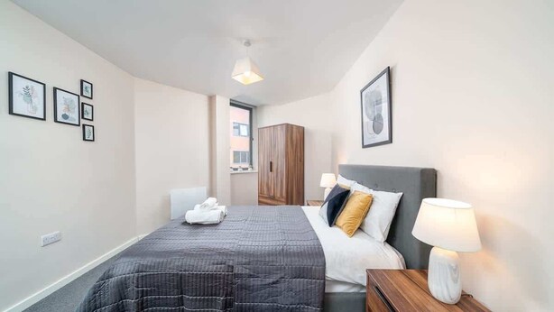 Una camera d'albergo con un letto, un comodino, una lampada e quadri appesi al muro.