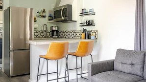 A compact kitchen with a refrigerator, microwave, coffee maker, and bar stools. - ABQ Stunner Studio! Cute kitchen! Private parking! (Albuquerque)