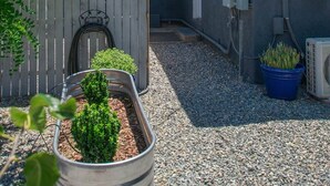 A residential building with a gravel driveway, a wooden fence, a bicycle, and potted plants. - ABQ Stunner Studio! Cute kitchen! Private parking! (Albuquerque)