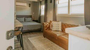 A compact RV interior with a kitchenette, a bed, and a seating area. - ABQ Hub Studio - Old Town Gem! (Albuquerque)