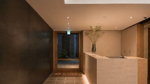 A modern reception desk with a minimalist design, a tiled floor, and a plant in a vase. - KIORI Collection Gokomachi (Kyoto)