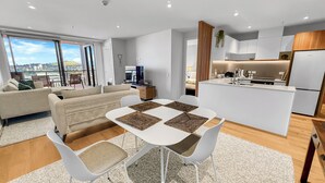 Un appartamento moderno con zona pranzo, cucina, soggiorno e un balcone con vista sulla città.