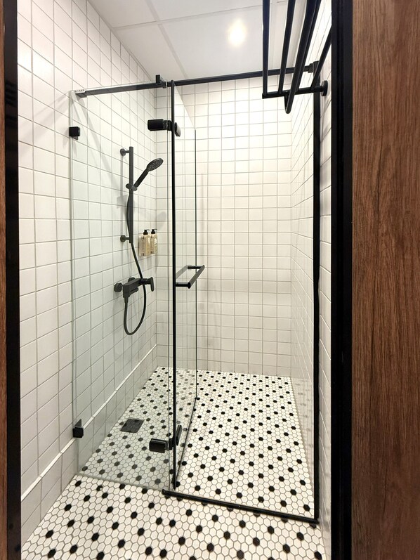 A shower with a glass door, tiled walls, and a patterned floor. - The Restro (Tainan)
