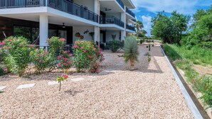 Ein mehrstöckiges Hotel mit Balkonen, einem Kiesweg und umliegender Bepflanzung.