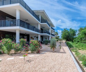 Ein mehrstöckiges Hotel mit Balkonen, einem Kiesweg und umliegender Bepflanzung.