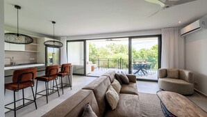Ein modernes Wohnzimmer mit einer Couch, Sesseln, einem Esstisch und einem Balkon mit Blick.