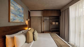 A hotel room with a bed, a painting, a wardrobe, and a window with curtains.