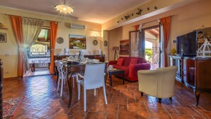 A dining area with a table set for four, a red sofa, and a television on a wooden cabinet. - Luxurious home in Partinico (Partinico)