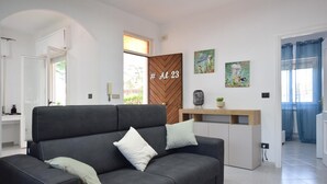 A modern living room with a sofa, a wooden door with a number, and artwork on the wall. - 3 bedroom stunning home in Trabia (Trabia)