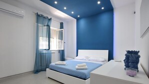 A bedroom with a bed, a nightstand, a window with sheer curtains, and a blue accent wall. - 3 bedroom stunning home in Trabia (Trabia)