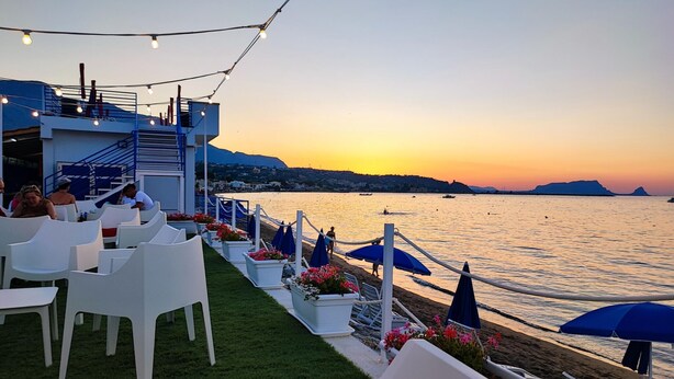 A seaside restaurant with outdoor seating, a view of the sea, and a building with a blue exterior. - 3 bedroom stunning home in Trabia (Trabia)
