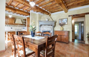 A rustic kitchen with wooden beams, a fireplace, and a dining table with chairs. - Lovely home in Monte Santa Maria Tibe (Monte Santa Maria Tibe)