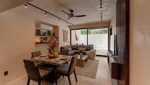 A modern living space with a dining area, a sofa, a TV, and a ceiling fan. - Talulah Living 3BR Apt - Private & Shared Pool (Tulum)