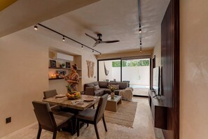 A modern living space with a dining area, a sofa, a TV, and a ceiling fan. - Talulah Living 3BR Apt - Private & Shared Pool (Tulum)