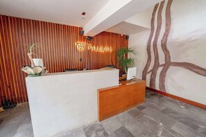 A reception desk with a wooden finish, a modern light fixture, and a wall with vertical wooden slats. - Talulah Living 3BR Apt - Private & Shared Pool (Tulum)