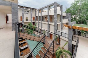 A multi-level building with a central staircase, outdoor seating, and a pool area. - Talulah Living 2BR Tulum Apt & Private Pool (Tulum)