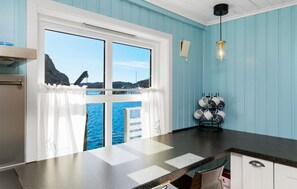A kitchen with a window overlooking a body of water, a black countertop, and a hanging light fixture. - 2 bedroom lovely home in Telavåg (Telavåg)