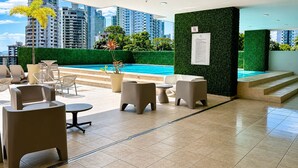 Eine Dachterrasse mit Pool, Sitzgelegenheiten im Freien und Blick auf Stadtgebäude.