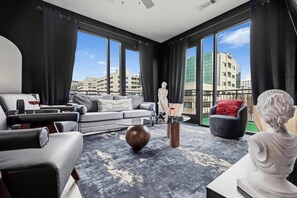 Ein modernes Wohnzimmer mit einer Couch, Sesseln, einem Couchtisch und einer Skulptur.