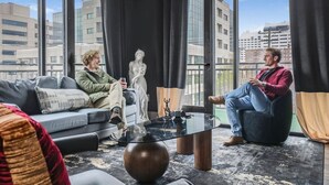 Een modern interieur met een bank, een glazen salontafel en een beeld.