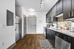 A modern kitchen with dark cabinets, stainless steel appliances, and a welcome sign. - Midtown. Mins to Broadway. Parking. Pool. Gym (Nashville)