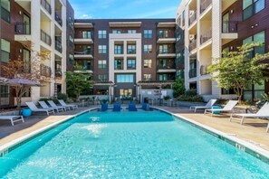 A modern apartment building with a central swimming pool, lounge chairs, and outdoor seating. - Midtown. Mins to Broadway. Parking. Pool. Gym (Nashville)