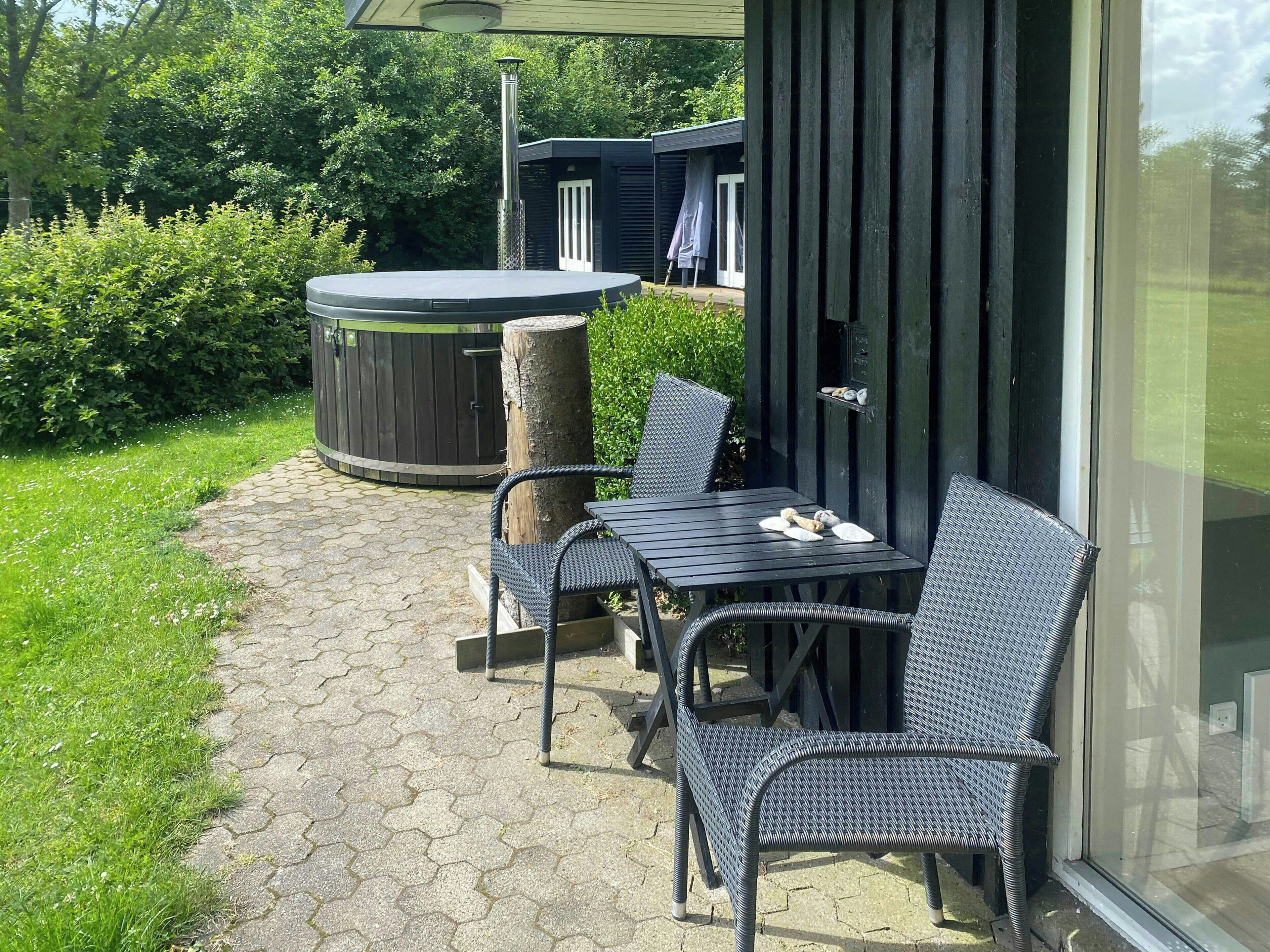 Une terrasse extérieure avec une table et des chaises, un jacuzzi et une plateforme en bois.