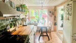 A kitchen with a stove, a dining table with chairs, and a refrigerator. - Charming cottage in scenic Brösarp Österlen (Kivik)