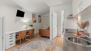 Una cocina moderna con horno integrado, un comedor con mesa y sillas, y un televisor montado en la pared.