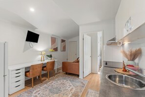 Eine moderne Küche mit Einbauofen, eine Essecke mit Tisch und Stühlen sowie ein an der Wand montierter Fernseher.
