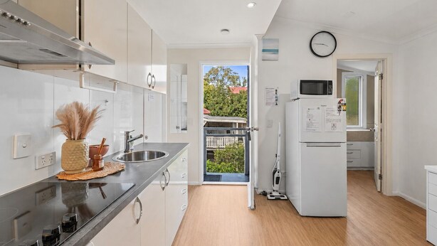 Una cocina moderna con electrodomésticos de acero inoxidable, una encimera negra y vistas al exterior.