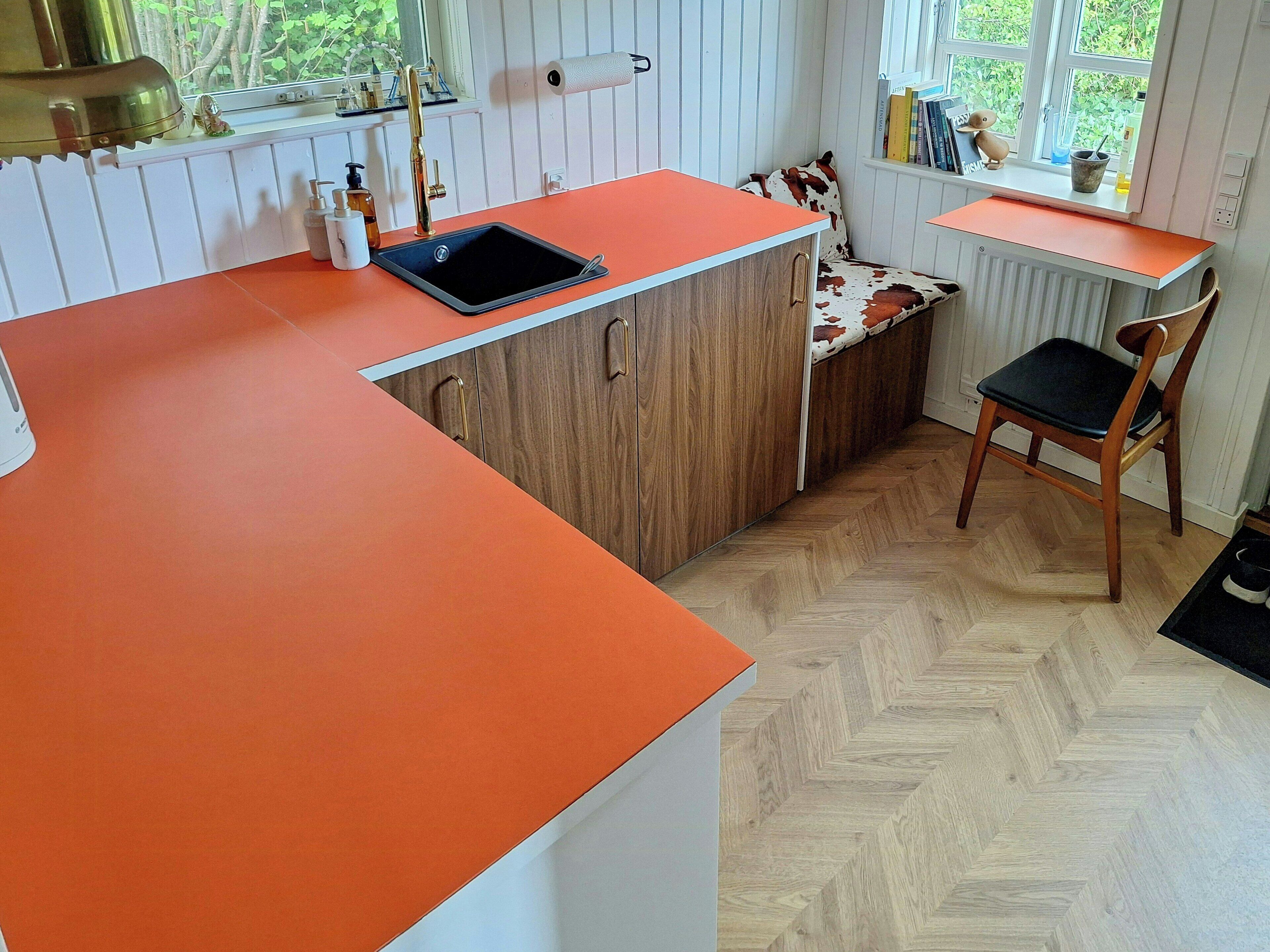 A compact kitchen with a sink, wooden cabinets, and a window with a view of greenery.