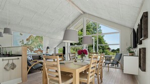 Une salle à manger spacieuse avec un plafond haut et de grandes fenêtres, des meubles en bois et une carte accrochée au mur.