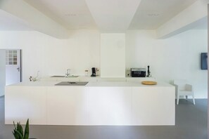 A modern kitchen with a white countertop, a coffee machine, and a microwave. - Design apartment in the historic Mittermurnthal (Neunburg vorm Wald)