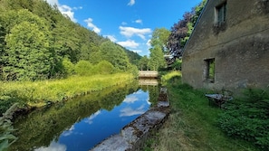 A serene riverside view with a rustic building, lush greenery, and a clear sky. - Design apartment in the historic Mittermurnthal (Neunburg vorm Wald)