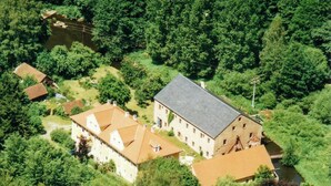 An aerial view of a large estate with multiple buildings, a river, and dense greenery. - Design apartment in the historic Mittermurnthal (Neunburg vorm Wald)