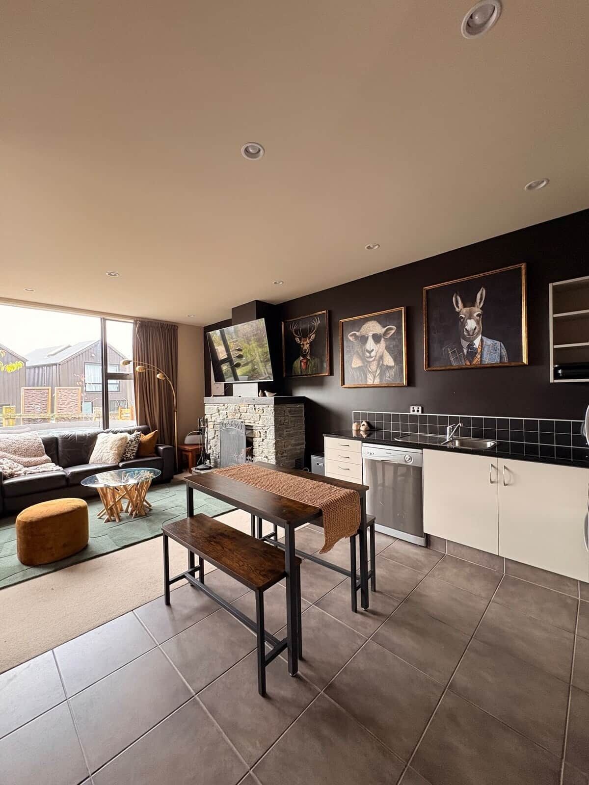 A modern kitchen with a dining area, a fireplace, and artwork on the wall.