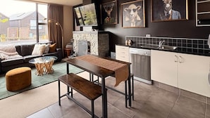 A modern kitchen with a dining area, a fireplace, and artwork on the wall. - Alpine Luxe Cardrona (Cardrona)