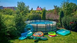 A backyard with a swimming pool, inflatable pool toys, and a small inflatable pool.