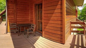 Uma cabana de madeira com varanda, uma mesa e um banco.