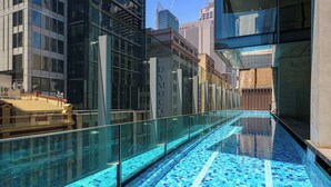 Un bâtiment moderne doté d’une façade en verre et d’un espace piscine orné de mosaïques bleues.