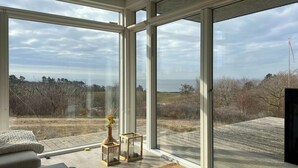 A room with large windows, a wooden floor, and a view of the outdoors.