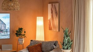 A living room with a sofa, a lamp, a plant, and a painting on the wall.