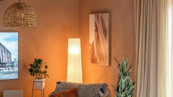 A living room with a sofa, a lamp, a plant, and a painting on the wall.