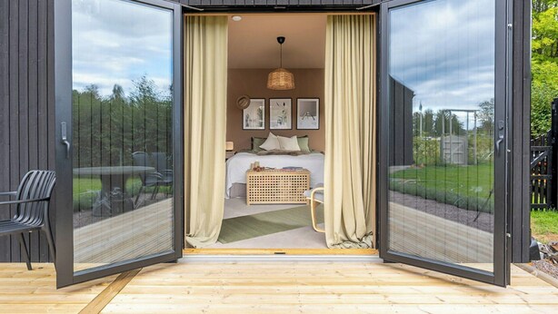 A modern bedroom with a bed, curtains, and a view of the outdoors.