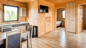 A wooden cabin interior with a kitchen, dining area, and a bedroom. - Awesome home in Darlowo with sauna (Darlowo)